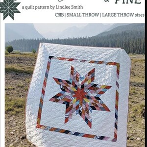 May include: A white quilt with a colorful Lone Star design. The quilt features a star pattern in the center, surrounded by a red and patterned border. The text "Patchwork Lone Star" and "Plains & Pine" are visible.
