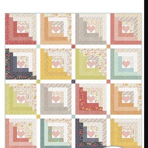 May include: A colorful quilt pattern with the text "Hearts at Home" and "Chelsi Stratton Designs." The quilt features square blocks with heart-shaped centers and various floral and geometric patterns in shades of pink, blue, green, and yellow.