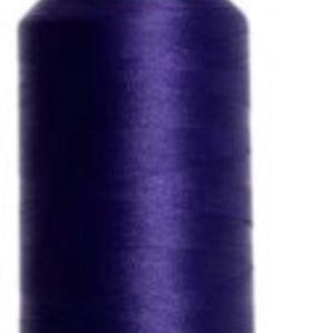 May include: A spool of dark purple thread with a green base and top. The thread is tightly wound, creating a cylindrical shape. The image is a close-up, highlighting the texture and color of the thread, suitable for sewing and embroidery projects.