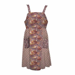 May include: A floral print apron with a square neckline and adjustable straps. The apron features a patchwork design with two front pockets and a plaid pattern on the lower half. The color palette includes shades of purple, orange, and brown.