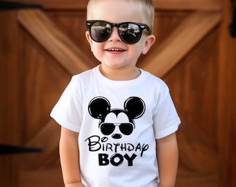 Puede incluir: Una camiseta blanca con un gráfico negro de Mickey Mouse con gafas de sol y el texto "Birthday Boy".