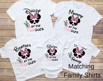 May include: Matching family t-shirts featuring a cartoon Minnie Mouse with pink polka dots and sunglasses. The shirts say "Daddy of the Twodles", "Mommy of the Twodles", "Brother of the Twodles", "Sister of the Twodles", and "I'm Twodles! Ashley".