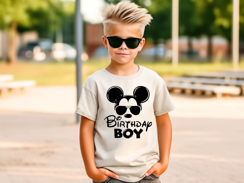 May include: A white t-shirt with a black Mickey Mouse graphic wearing sunglasses and the text "Be Birthday Boy".