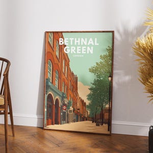 May include: A framed art print featuring a street scene in Bethnal Green, London. The artwork depicts a row of brick buildings with shops and trees lining the street. The print has a vintage aesthetic with a color palette of orange, teal, and brown.