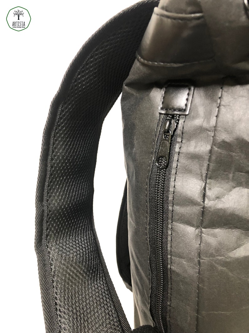 May include: A black backpack with a zippered pocket and a mesh padded strap. The backpack is made of a water-resistant material.