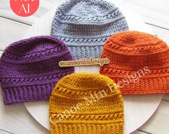 Peut inclure: Quatre bonnets au crochet en violet, gris clair, orange et jaune moutarde. Chaque bonnet présente un motif de points texturés avec un bord côtelé. Une étiquette en bois avec @canoemtndesigns et le texte Canoe Mtn Designs sont visibles.