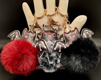 May include: Three black bat-shaped keychains with fuzzy pom-poms in red, black and gray.