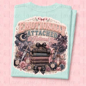 May include: A light blue t-shirt featuring the text "Emotionally Attached to Fictional Men" in a decorative font. The design includes a stack of books, roses, swords, and a dragon, creating a fantasy theme.
