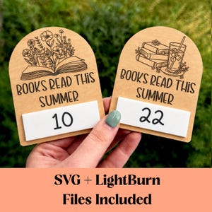 Op de afbeelding: Twee houten boekenvolgers met de tekst "BOOKS READ THIS SUMMER". Eén tracker toont "10" en de andere "22". De trackers hebben gegraveerde illustraties van boeken, bloemen en een drankje. De tekst "SVG + LightBurn Files Included" staat onderaan.