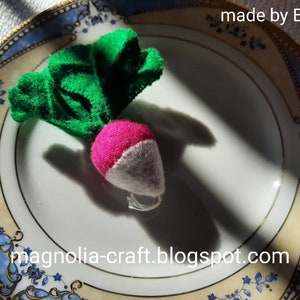 May include: A felt radish with green leaves on a white plate with a blue and gold pattern. The text "made by EDITH" and "magnolia-craft.blogspot.com" are visible on the plate.