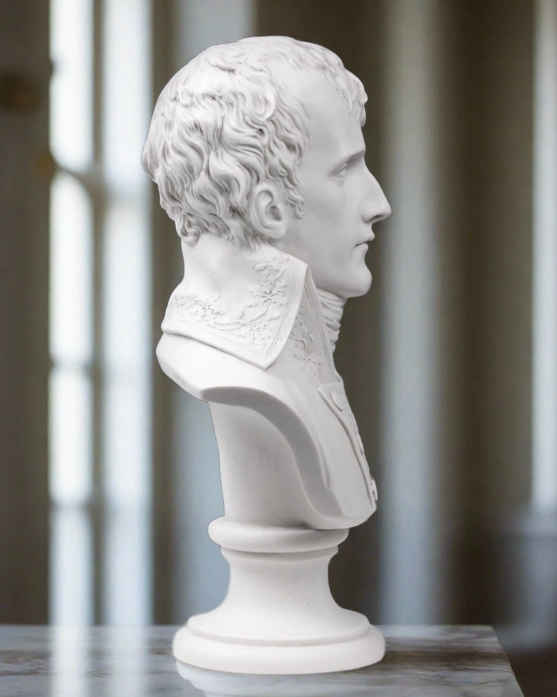 May include: White plaster bust sculpture of a man with short hair, wearing a collared shirt. The bust is on a white pedestal.