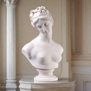May include: White marble bust sculpture of a woman with her head tilted down. The sculpture is on a white pedestal.