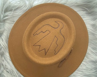 Oval tan standard brim fedora hat, decorated with thunderbird, and cacti.