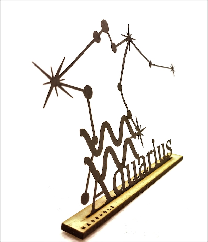 May include: A black metal cutout of the Aquarius constellation with the word "Aquarius" written below. The cutout is mounted on a small wooden base with the word "MADEHOLZ" printed on it.