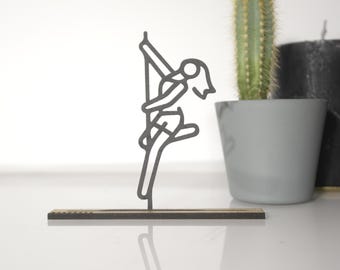 Könnte beinhalten: Eine schwarze Metallsilhouette einer Person, die an einem Pfosten hängt, montiert auf einem Holzsockel.
