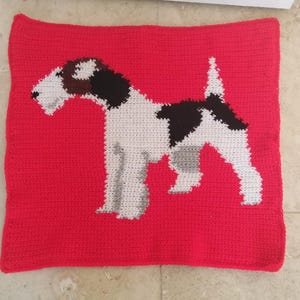 May include: A red crocheted throw pillow with a white and black crocheted wirehaired fox terrier dog design.
