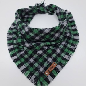May include: Green and black plaid dog bandana with frayed edges and a brown leather tag that says "Mountain Pup".
