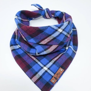 May include: Blue, purple, and white plaid bandana with a brown leather patch that says "Adventure Awaits".