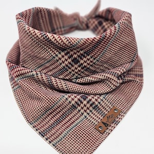 May include: A red, white, and blue plaid dog bandana with a brown leather patch that says "Adventure Awaits".