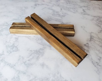 May include: Two wooden display stands with a slot in the center. The stands are made of dark brown wood and are stacked on top of each other.