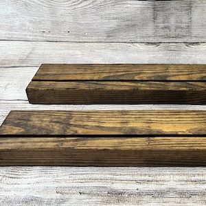 May include: Two wooden shelves, stained a dark brown, are stacked on top of each other. The shelves have a rustic, natural look and are perfect for displaying items.