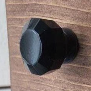 May include: Black, faceted, geometric cabinet knob with a shiny finish.