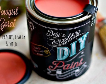 May include: A can of coral-colored paint labeled "Cowgirl Coral" with the tagline "Peachy, Beachy & Wild". The can is labeled "Debi's design diary DIY Paint".