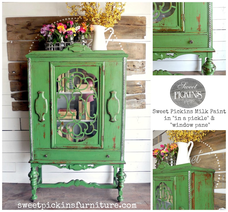 May include: A green antique cabinet with glass doors and a distressed finish. The cabinet has a drawer and sits on four turned legs. The cabinet is painted with Sweet Pickins Milk Paint in "in a pickle" and "window pane".