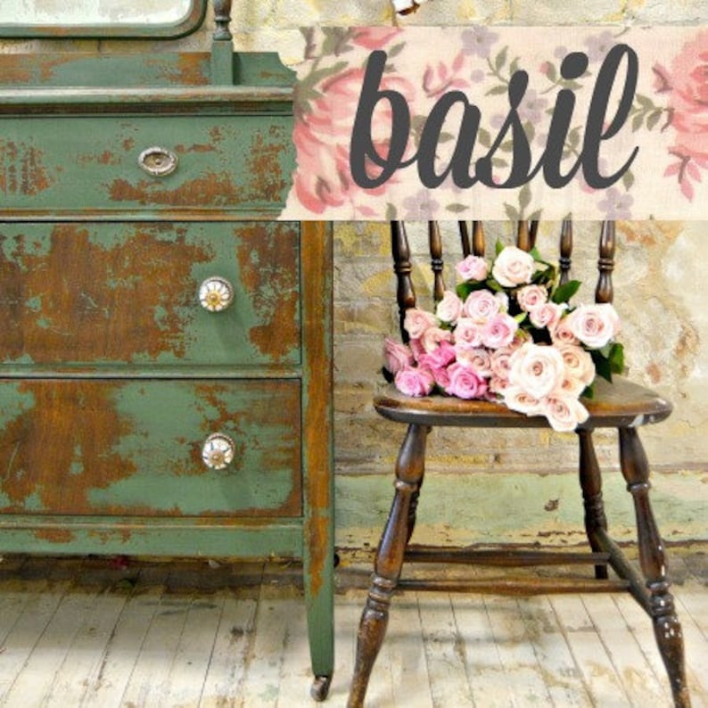 May include: A distressed green dresser with three drawers and white ceramic knobs. The dresser is in front of a brick wall and a chair with a floral pattern. The word "basil" is written in black on a floral background.