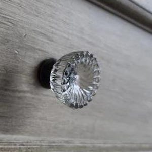 May include: Clear glass cabinet knob with a faceted design and a black metal base.
