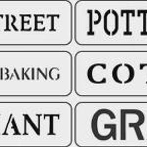 May include: Six rectangular signs with black text on a white background. The signs read: "MAIN STREET", "POTTERY CO.", "GROCERY & BAKING", "COTTON", "MERCHANT", and "GRAINS". The signs are arranged in two rows of three.
