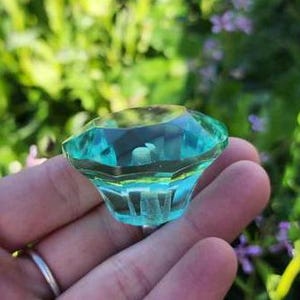 May include: A teal blue glass cabinet knob with a faceted design.