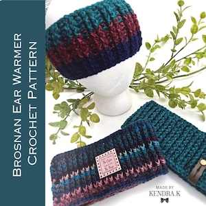 May include: Two crocheted ear warmers in a teal, navy, and burgundy color pattern. The ear warmers are made with a textured stitch. The ear warmer on the left has a small label that says "The Cabin" and "The Things". The ear warmer on the right has a brown leather strap with a metal buckle. The text "MADE BY KENDRA.K" is at the bottom of the image.