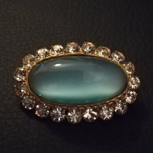 Vintage dress brooch, blue stone set in gold colour metal with diamond style edging