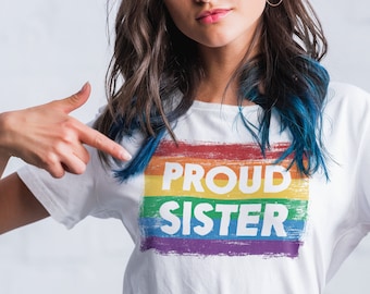 May include: A white t-shirt with a rainbow graphic and the text "PROUD SISTER" printed on it.