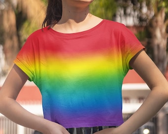 May include: A person wearing a rainbow tie-dye cropped t-shirt with a white and blue striped skirt.
