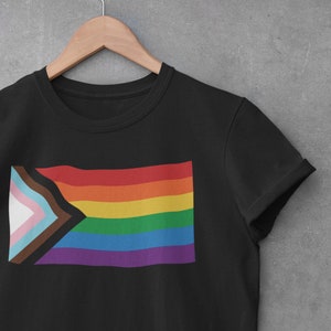 May include: Black t-shirt with a rainbow pride flag with a brown, light blue, pink, and white triangle in the corner.