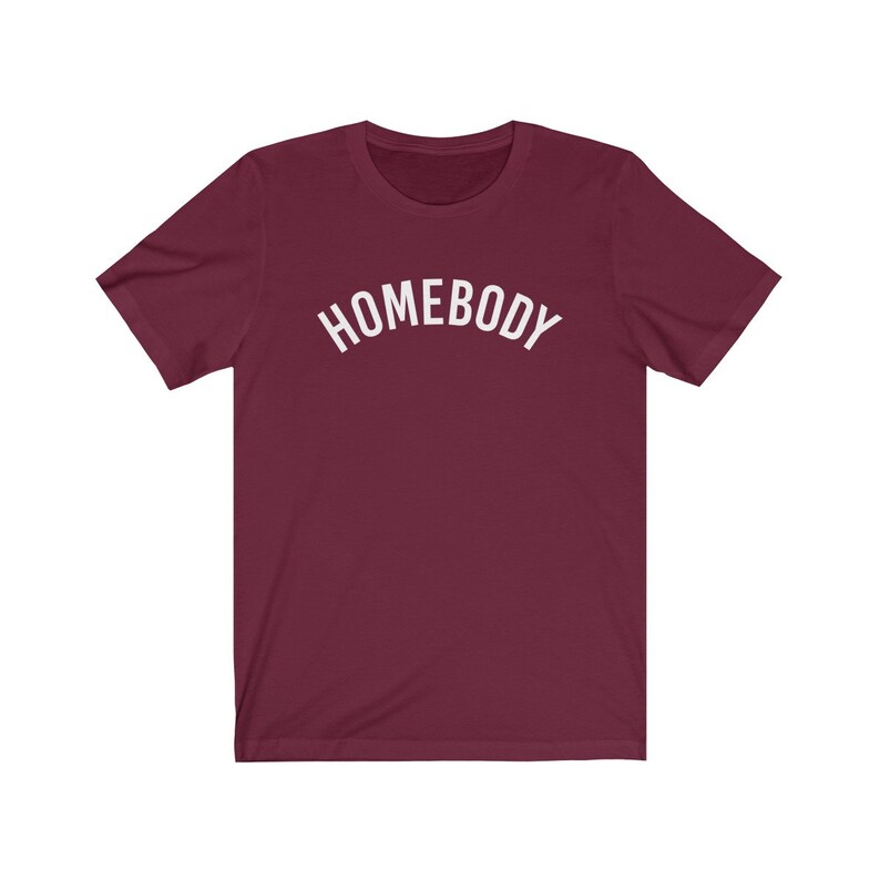 May include: A maroon t-shirt with the word "HOMEBODY" printed in white in an arc across the chest.