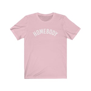 May include: A pink short-sleeved t-shirt with the text "HOMEBODY" printed in white on the front.