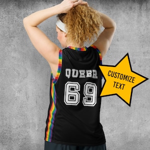 May include: Black basketball jersey with rainbow stripes on the sides. The jersey has the word "QUEER" and the number "69" printed on the back. A yellow star with the text "CUSTOMIZE TEXT" is on the right side of the jersey.