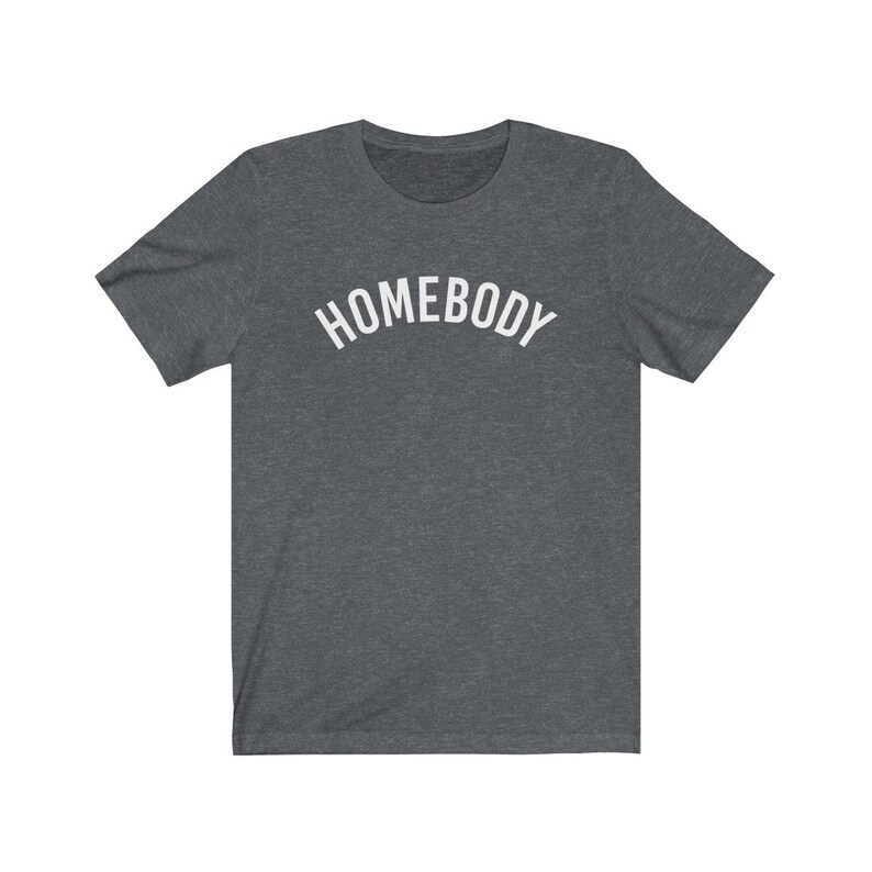 May include: A dark heather grey t-shirt with the word "HOMEBODY" printed in white in an arched font.