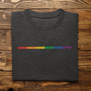 May include: A dark gray t-shirt with a thin horizontal stripe of rainbow colors.