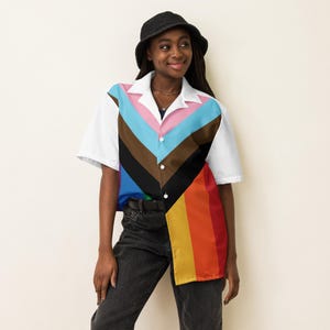 May include: A white button-down shirt with a colorful geometric pattern. The pattern features a chevron design with stripes of pink, blue, brown, black, green, yellow, orange, and red.