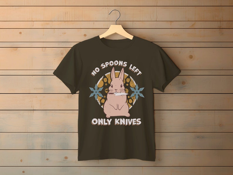 May include: A dark green t-shirt with a pink bunny rabbit holding a knife. The text "No Spoons Left Only Knives" is printed on the shirt.