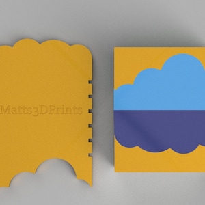 May include: A yellow plastic scraper with a scalloped edge and the text "Matts3DPrints" on the front. Next to it is a yellow square with a blue cloud on top of a purple cloud.