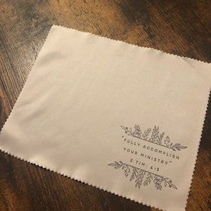 May include: A beige microfiber cleaning cloth with a black floral design and the text "FULLY ACCOMPLISH YOUR MINISTRY" 2 TIM. 4:5