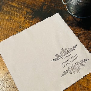 May include: A white microfiber cleaning cloth with a black floral design and the text "#CUMPLE COMPLETAMENTE TU MINISTERIO 2 TIM. 4:5".