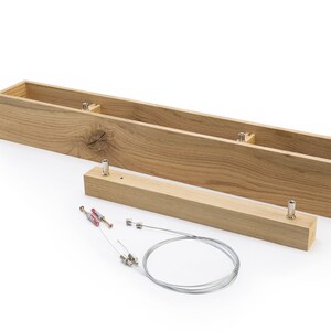 May include: A wooden box with two separate pieces, a long rectangular box and a shorter rectangular piece. The box is made of light brown wood with a natural grain pattern. The box is disassembled and laid out on a white surface. The box is designed to be used as a light fixture.