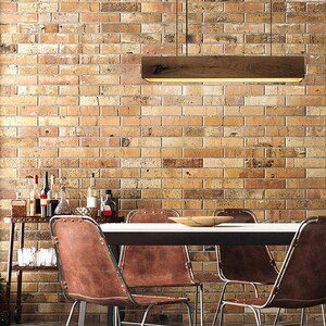 May include: A dining room table with four brown leather chairs with metal frames. The table has a white top and a black base. A wooden light fixture hangs above the table.