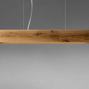 May include: A wooden pendant light fixture with a rectangular shape and a natural wood finish.